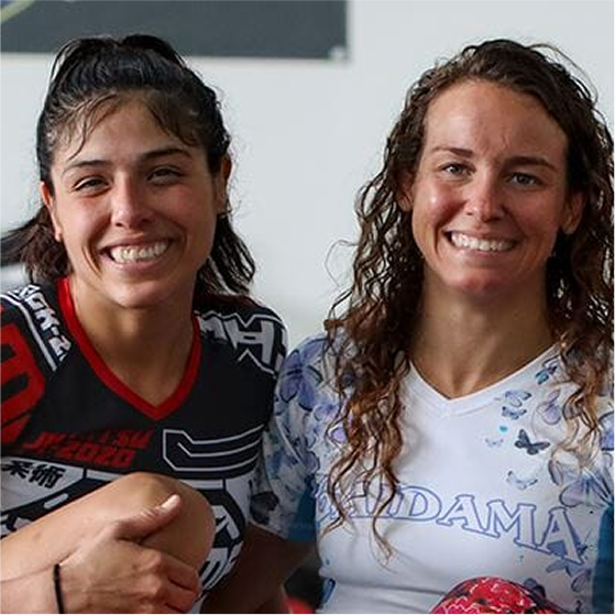Two people smiling, wearing sports attire, sitting closely together indoors.
