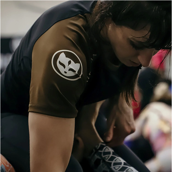 Person in a brown shirt with a fox logo, bending over.