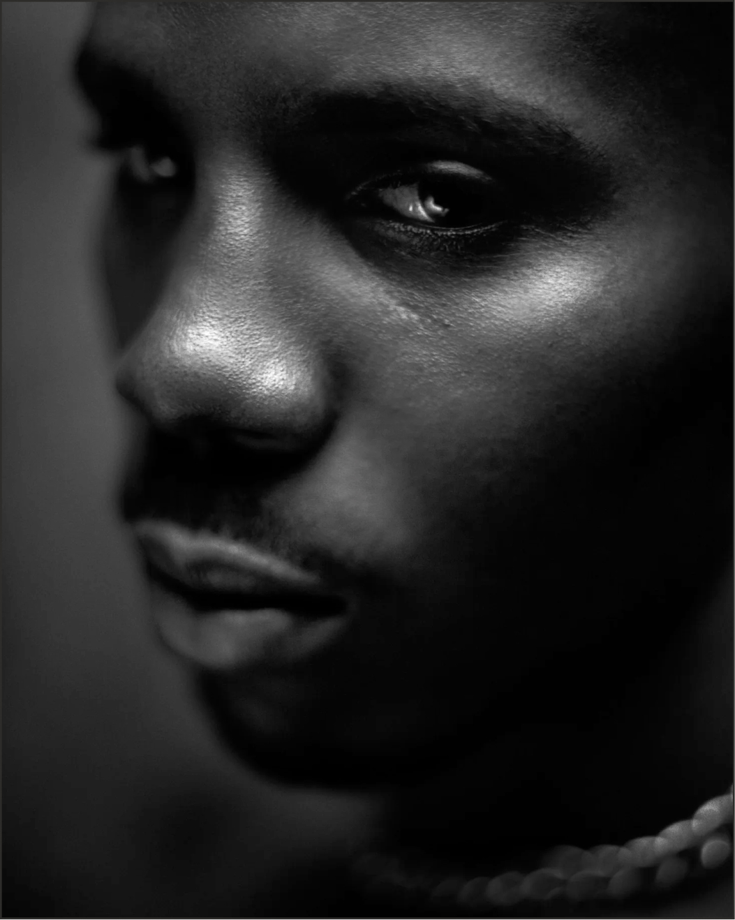 A dramatic, black and white close-up photograph of a young man's face.