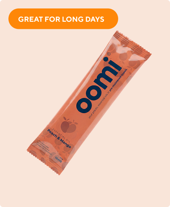 An individually wrapped oomi brand Peach & Mango essential oil pre-moistened towel on a light background.