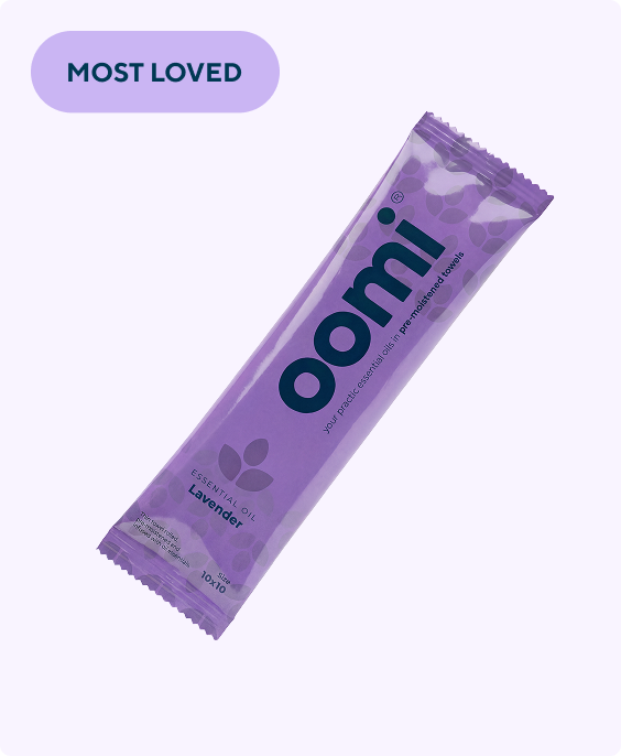 A purple, single-use packet of an Oomi lavender essential oil towelette, labeled 'Most Loved'.