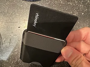 A hand holding a black cardholder with a card partially inserted.