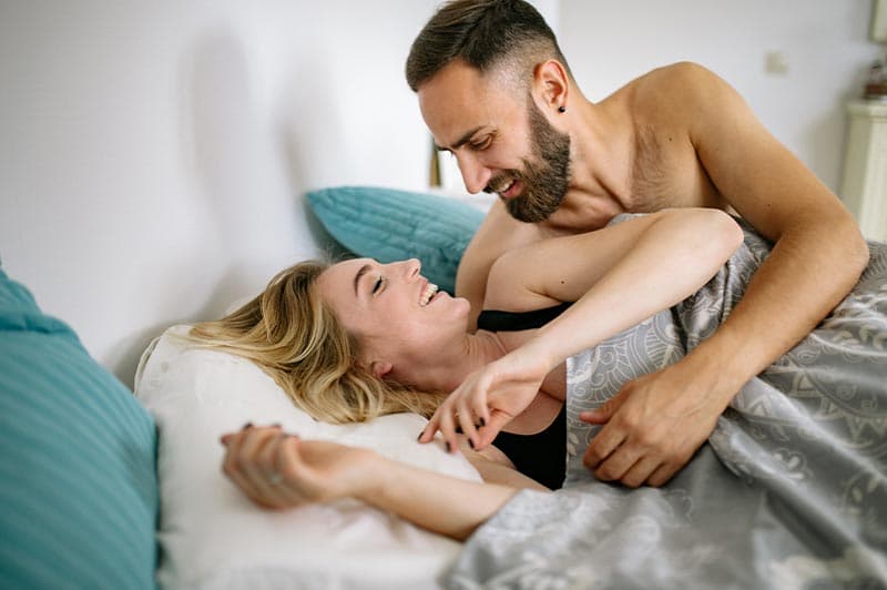 A couple laughing and embracing in bed.