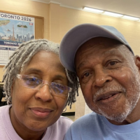 A smiling older man and woman pose for a close-up photo.