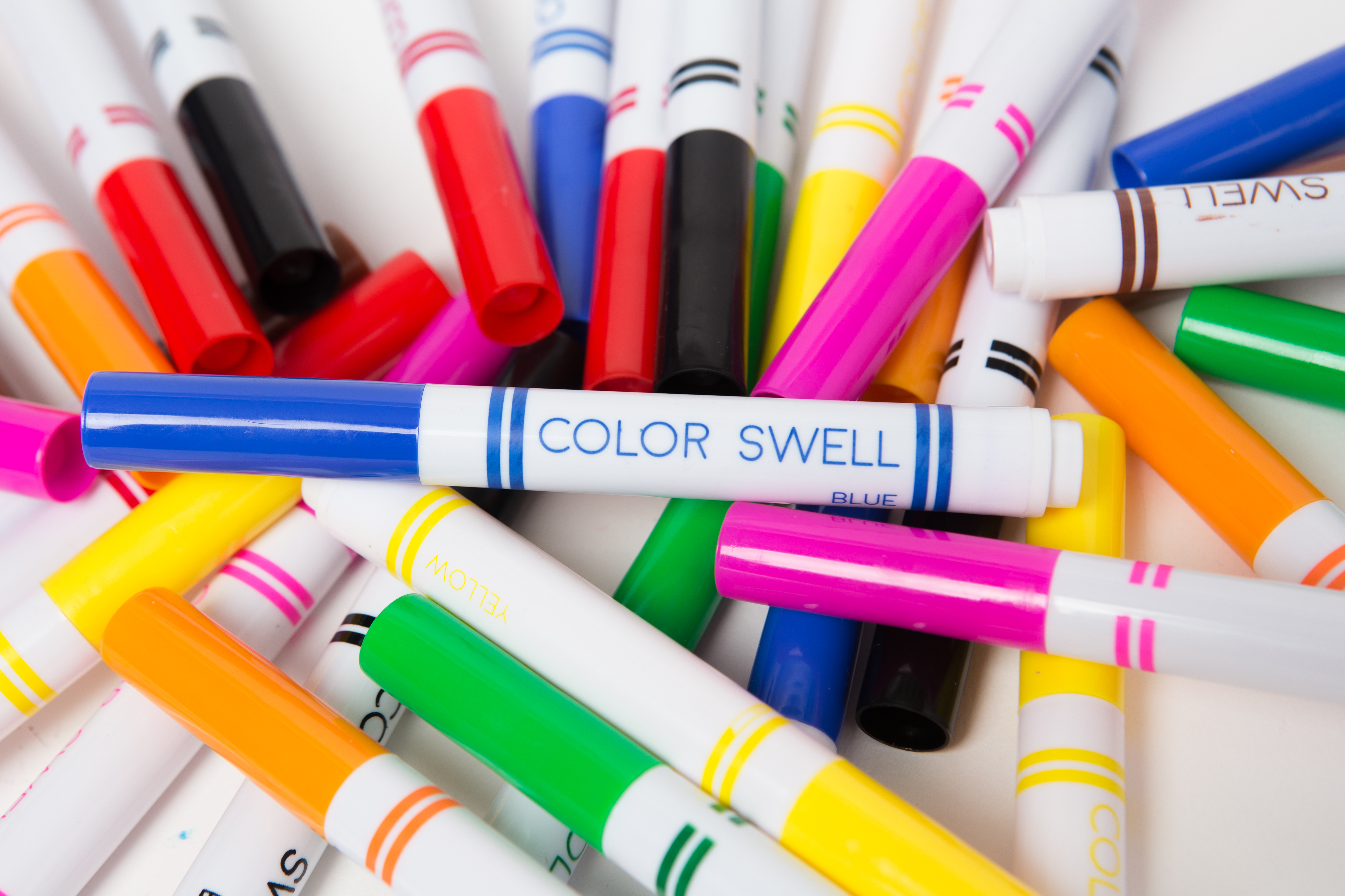 Assorted colorful markers scattered on a white surface.