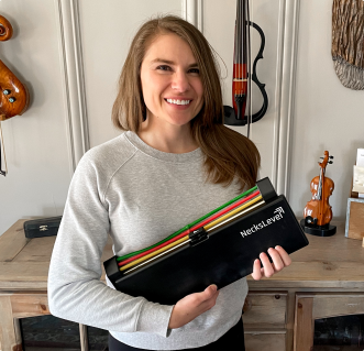 A person smiling and holding a product labeled 'NecksLevel' in a room with musical instruments.