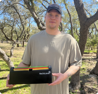 Man holding exercise equipment box outdoors among trees.