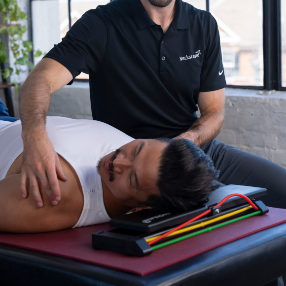 Person lying on a table with another person assisting in an exercise.