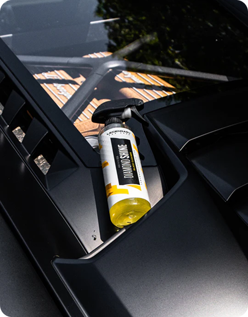 A spray bottle of Diamond Shine cleaner sits on the vent of a matte black vehicle.