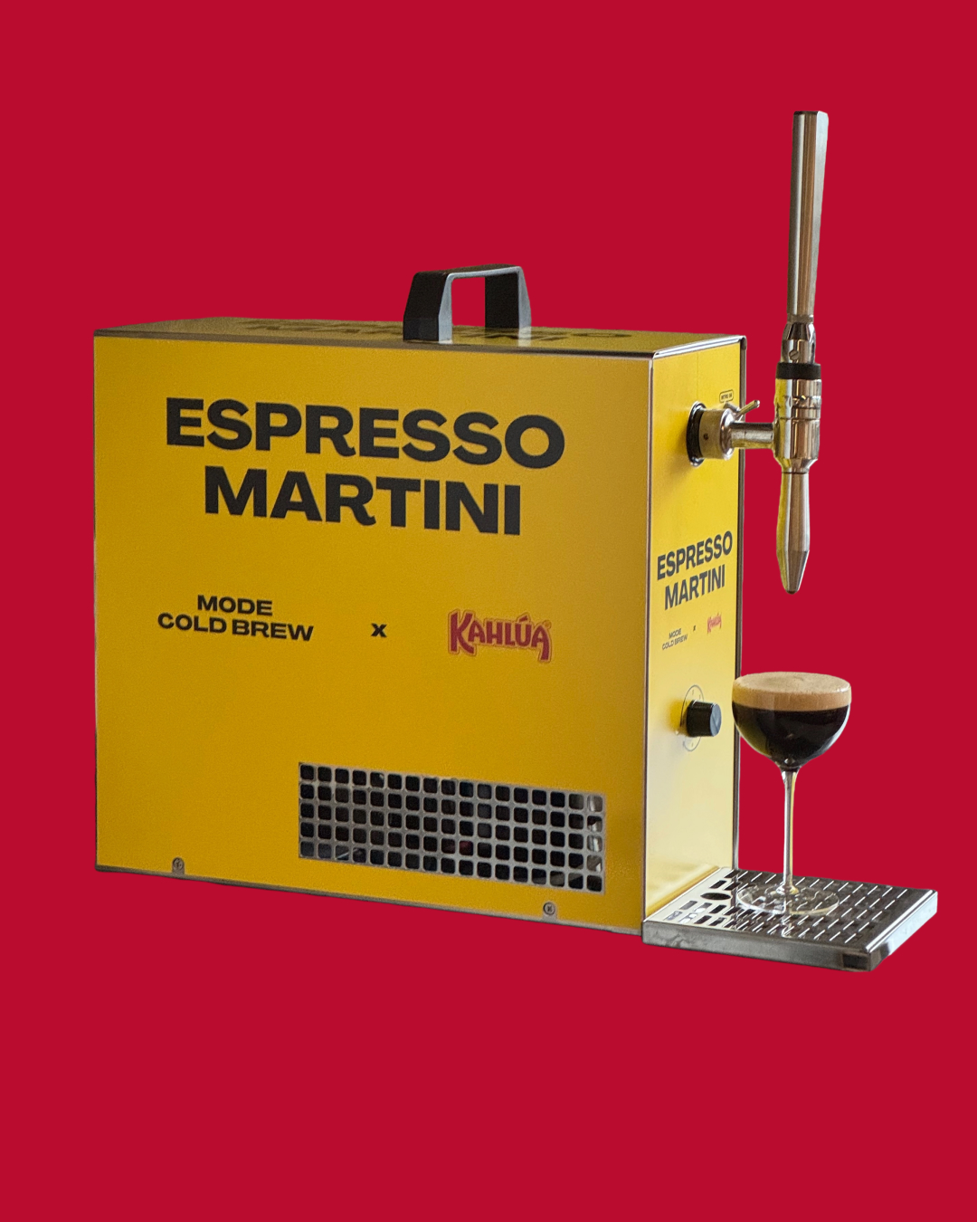 Yellow espresso martini machine with tap and glass on red background.