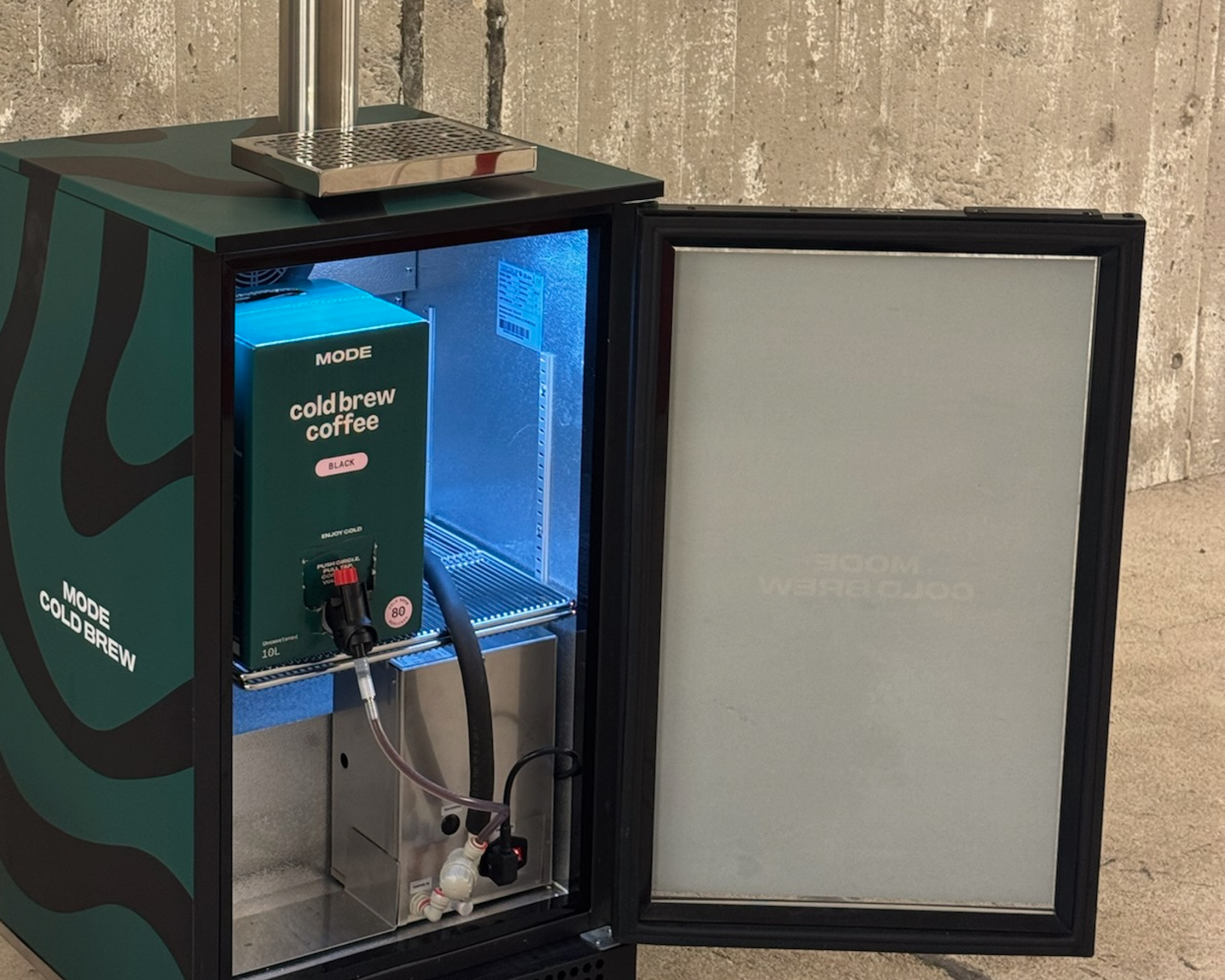 Cold brew coffee dispenser with open door, revealing a coffee box inside.
