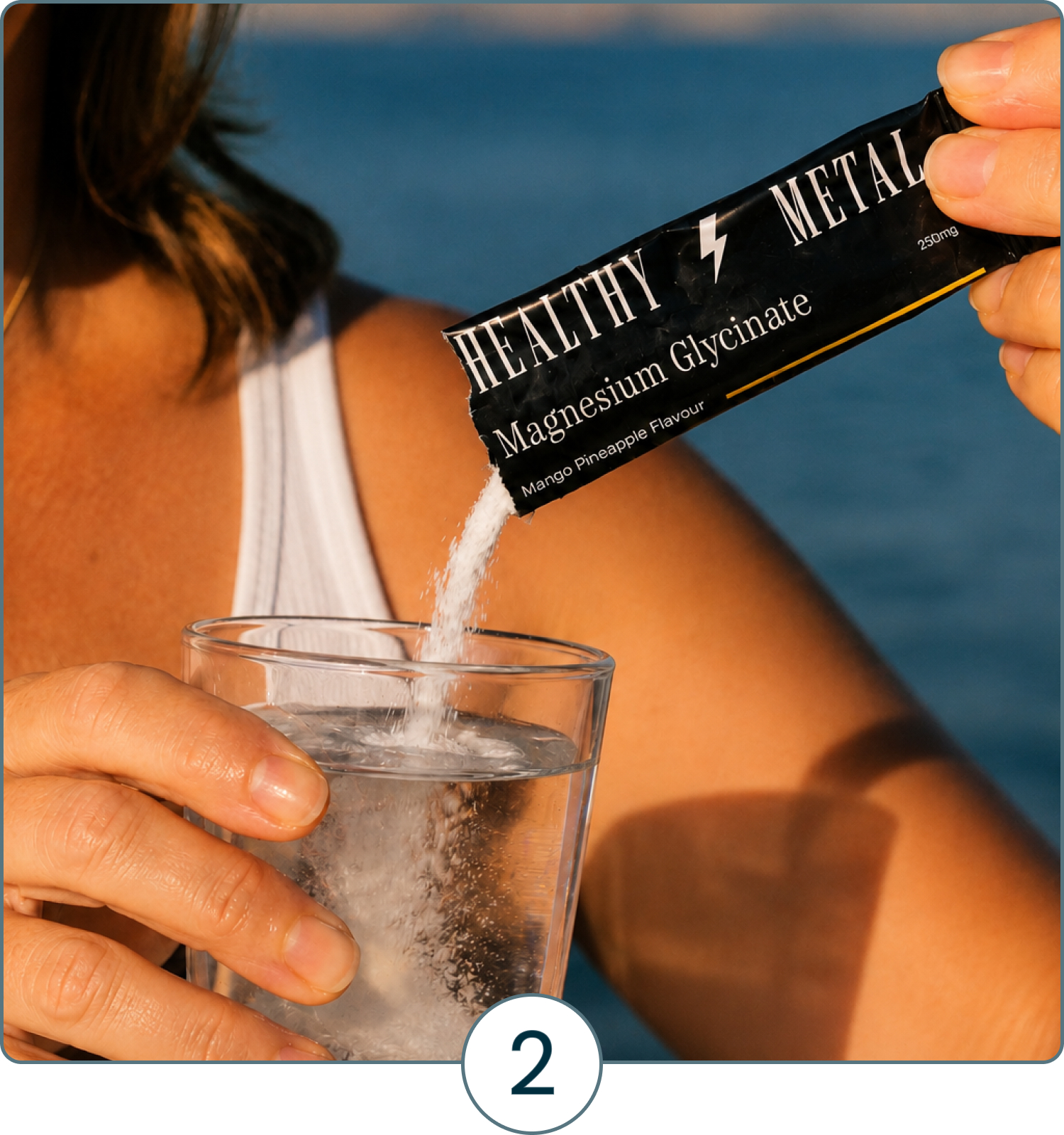 A person pours Healthy Metal Magnesium Glycinate powder from a sachet into a glass of water outdoors.