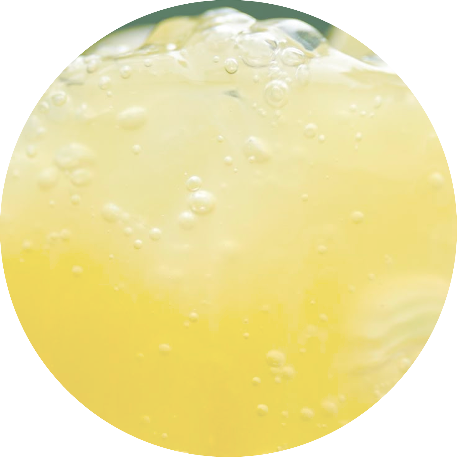 A close-up circular shot of a bubbly yellow beverage with ice cubes.