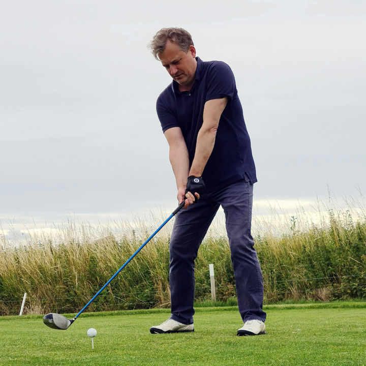 Man preparing to hit a golf ball on a grassy course.