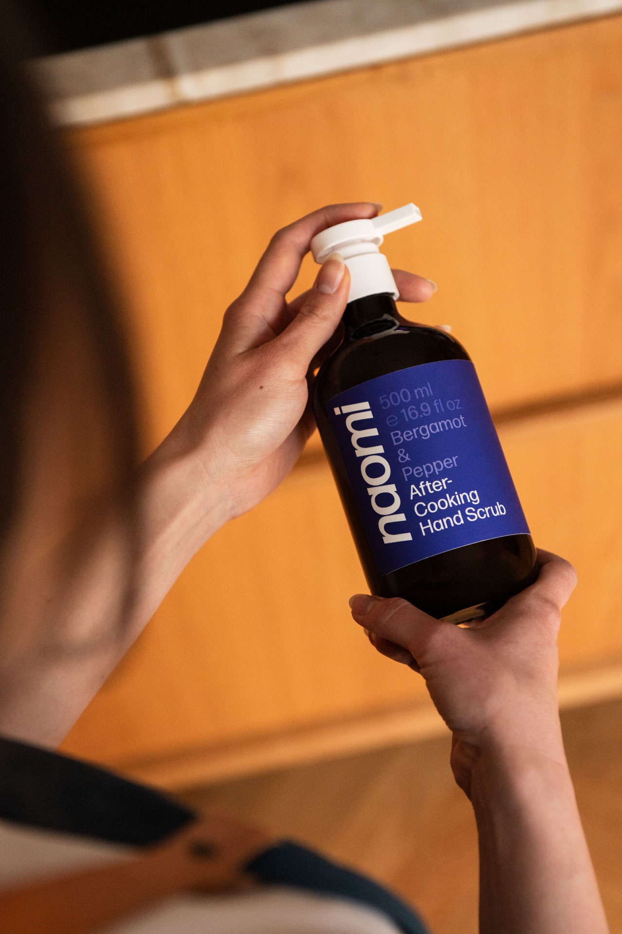 Person holding a bottle of after-cooking hand scrub.