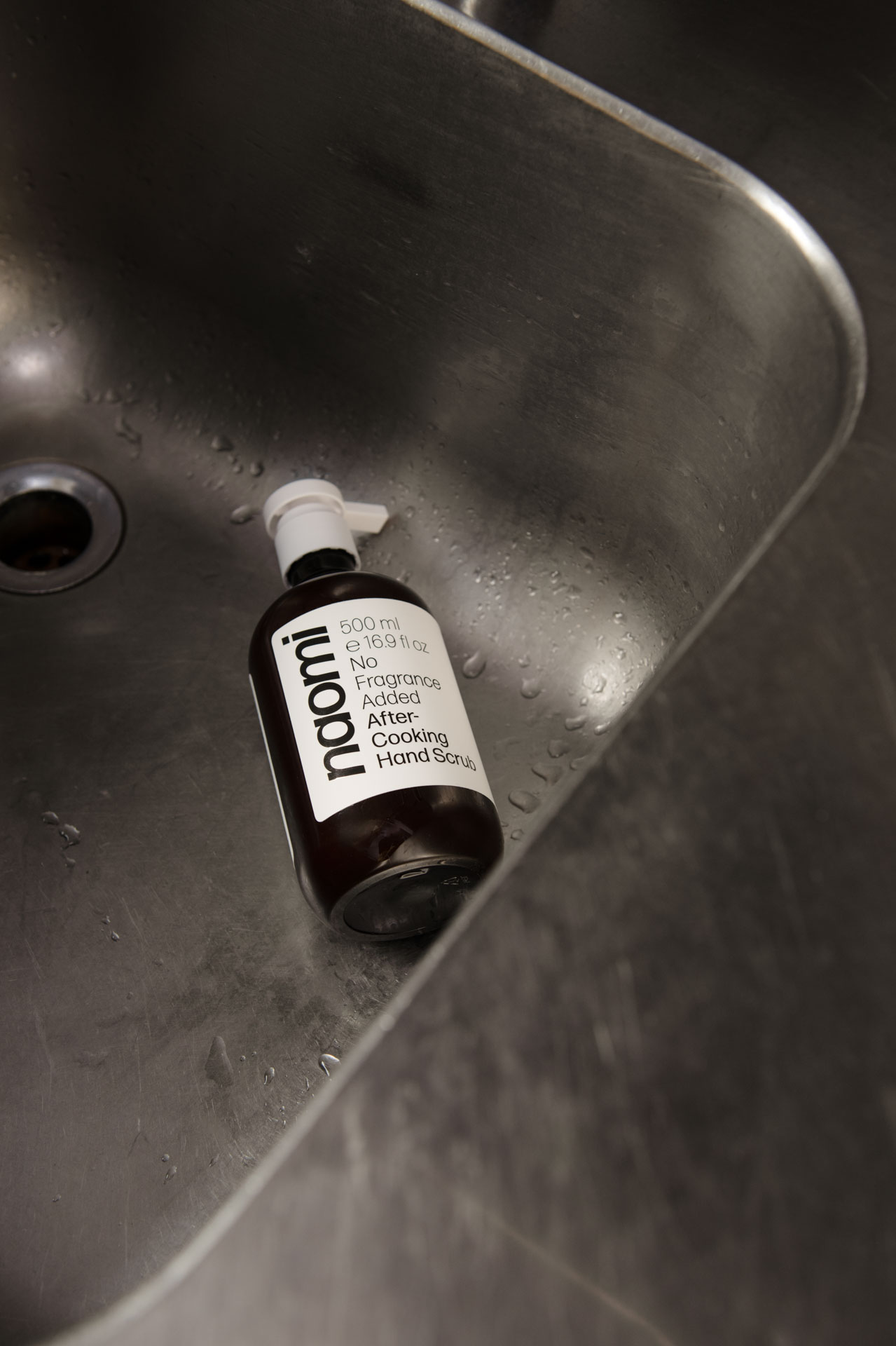 Bottle of hand scrub in a stainless steel sink.