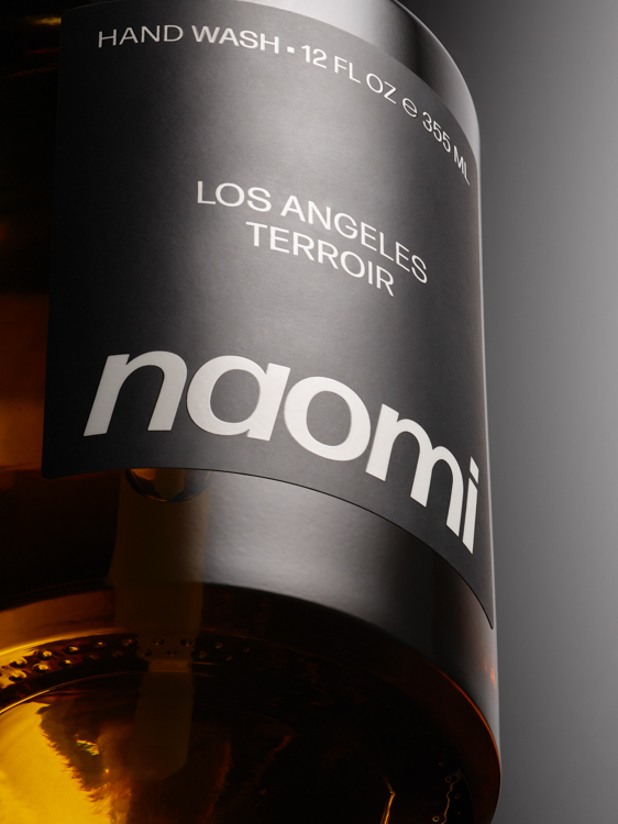 Close-up of a bottle labeled 'naomi,' 'Los Angeles Terroir,' 'Hand Wash 12 FL OZ 355 ML.'
