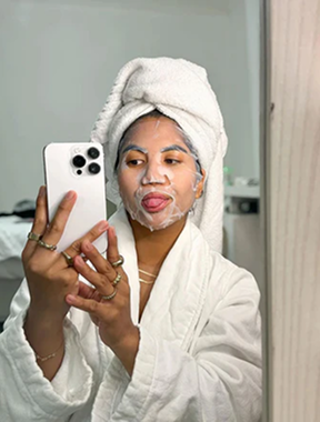 A close-up of three skincare serum bottles arranged in front of their packaging and some dried flowers.