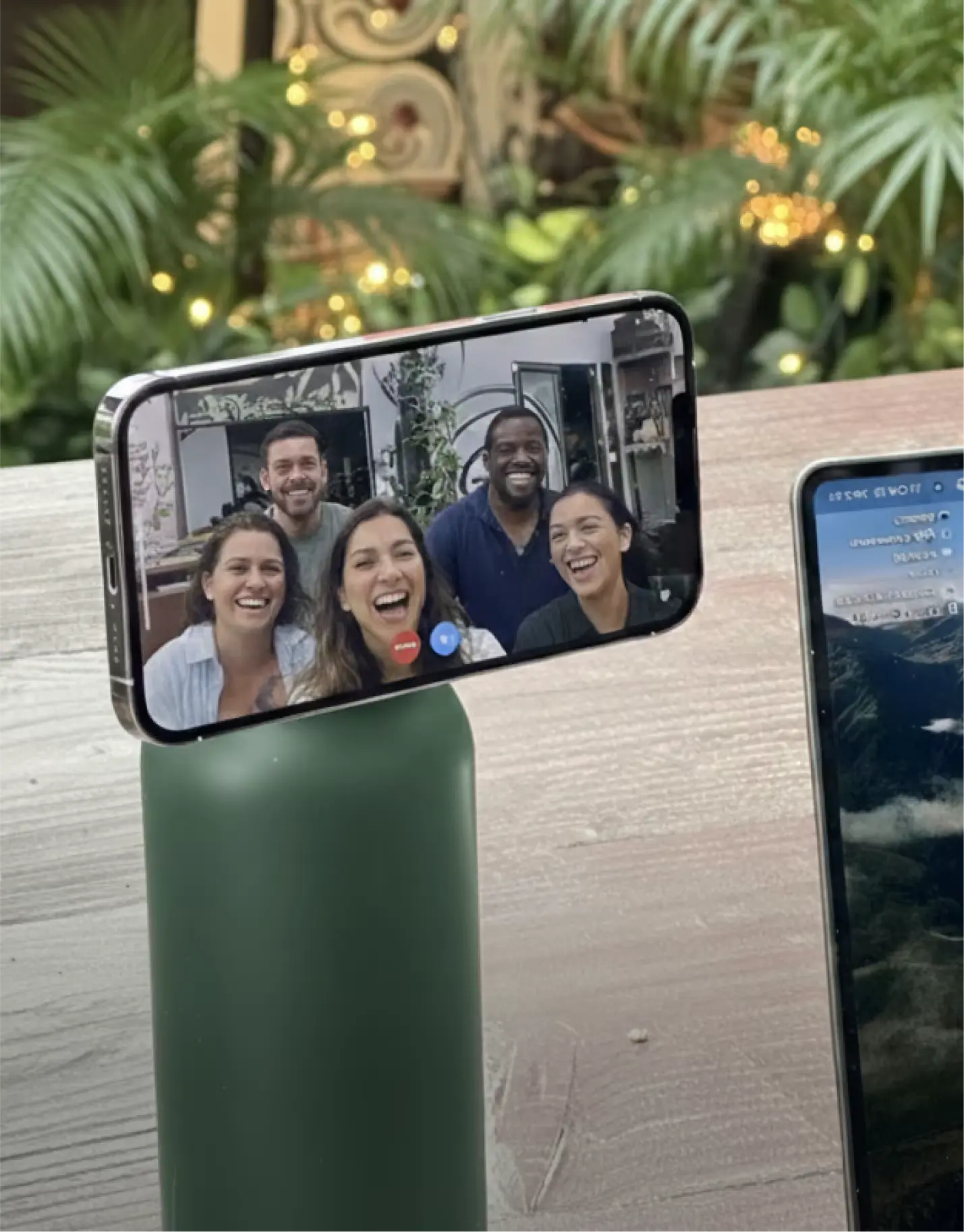 Smartphone on bottle shows video call with five smiling people.