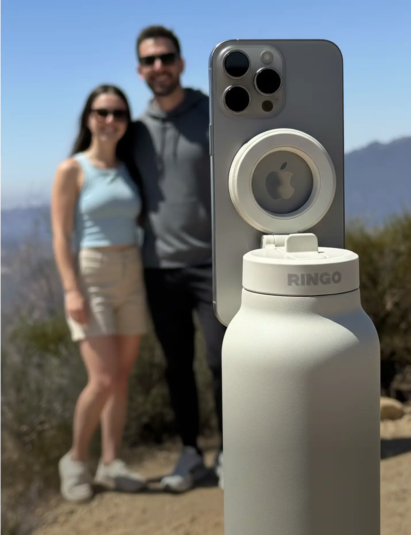 Smartphone mounted on a bottle with a blurred couple in the background.