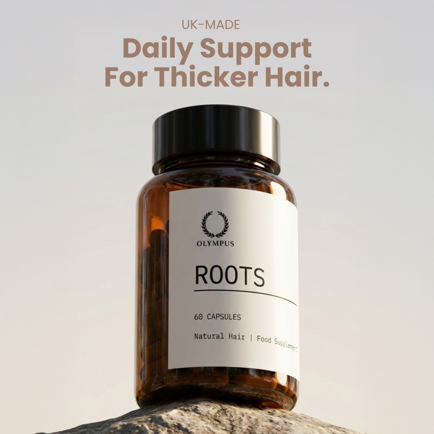 A brown bottle of Olympus Roots hair supplement capsules sitting on a rock against a plain sky.