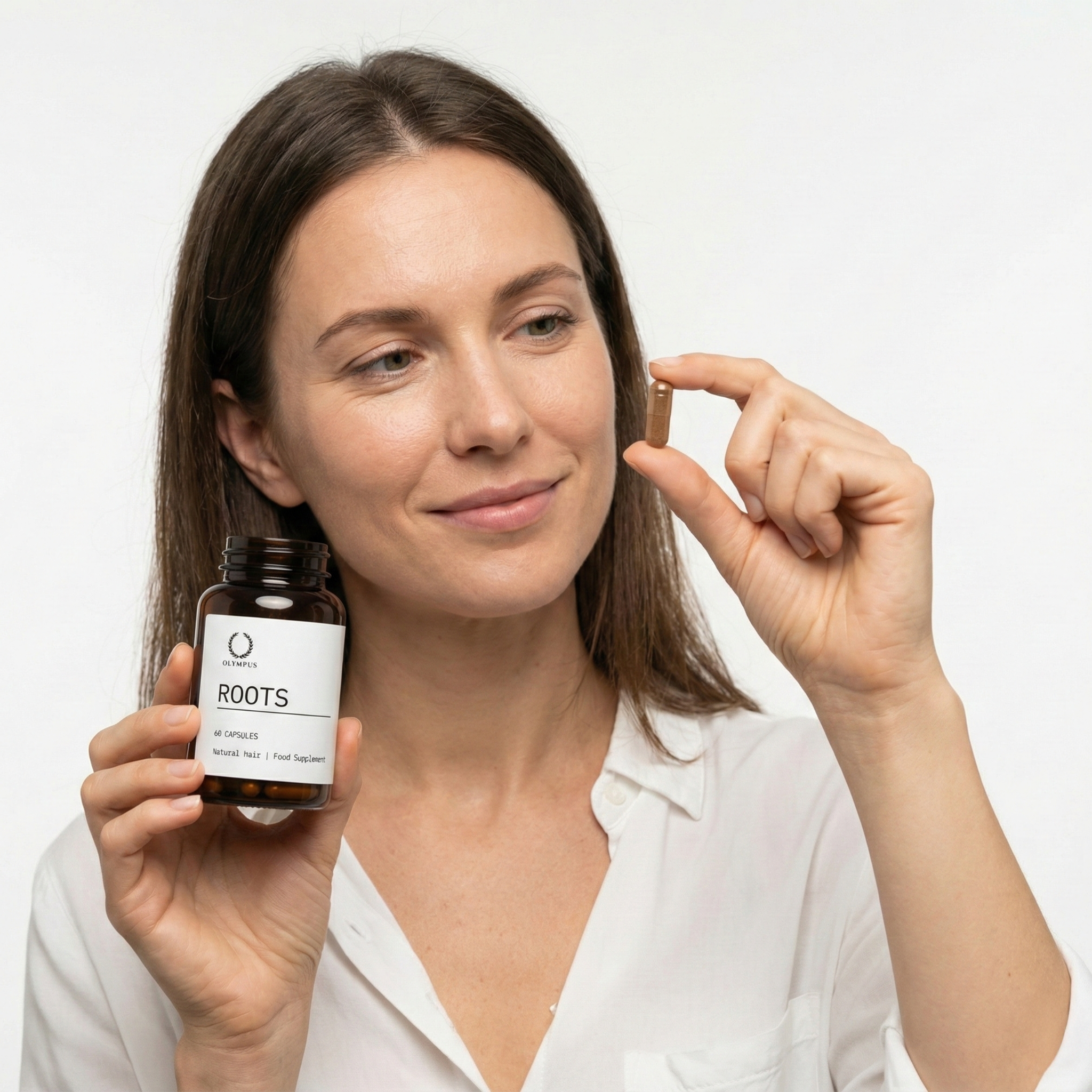 Person holding a bottle labeled 'Roots' and a single capsule.