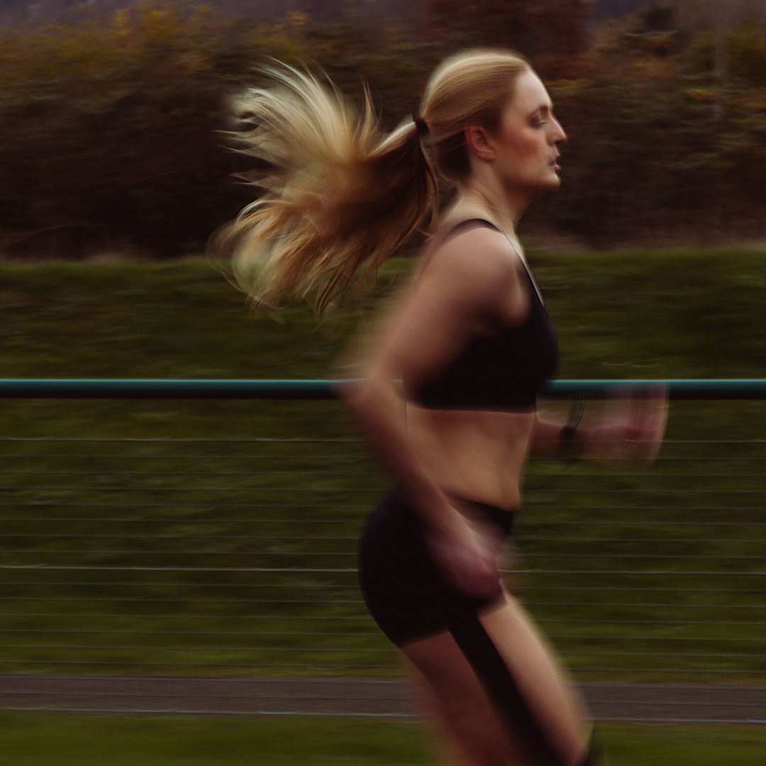 Woman with blonde hair running outdoors, motion blur effect.