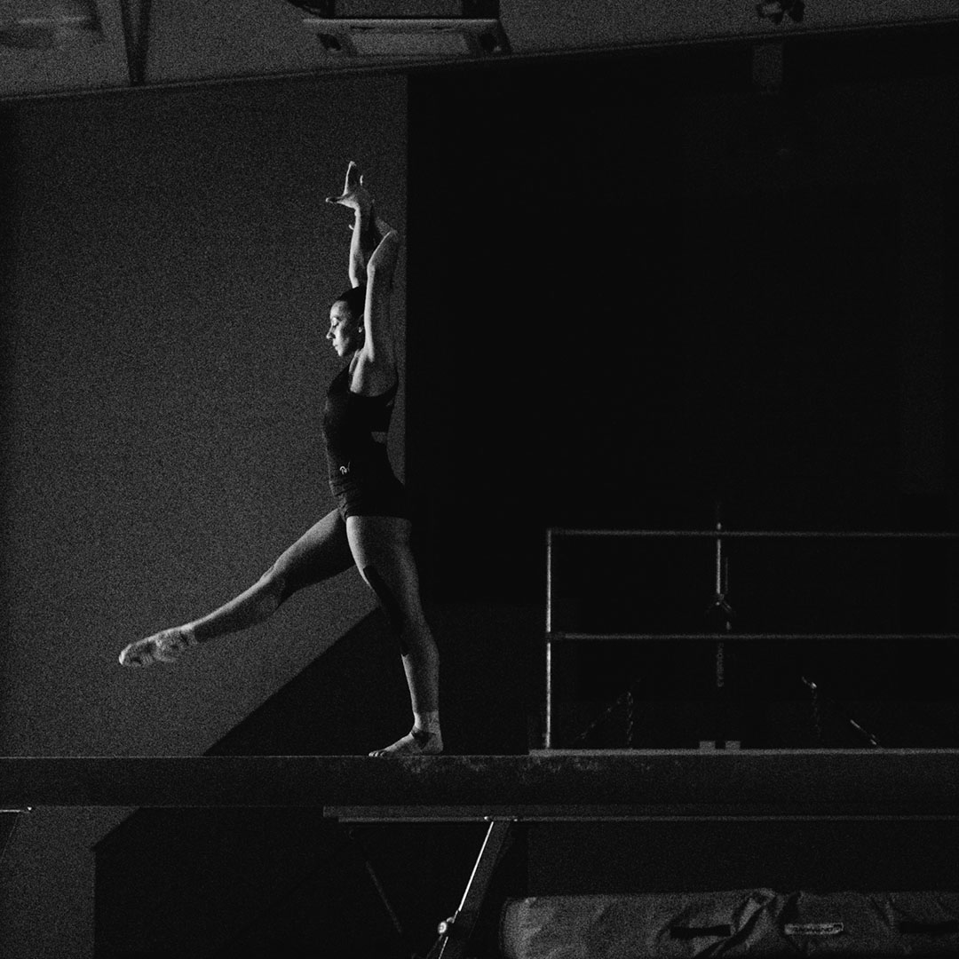 Black and white image of a gymnast balancing on a beam.
