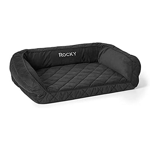 A quilted black Orvis dog bolster bed personalized with the name 'Rocky' embroidered on the headrest.