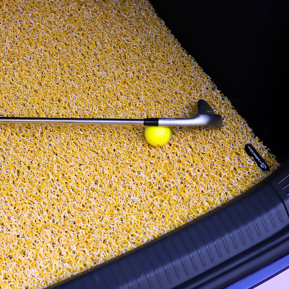 A golf club and yellow ball on a textured yellow surface.