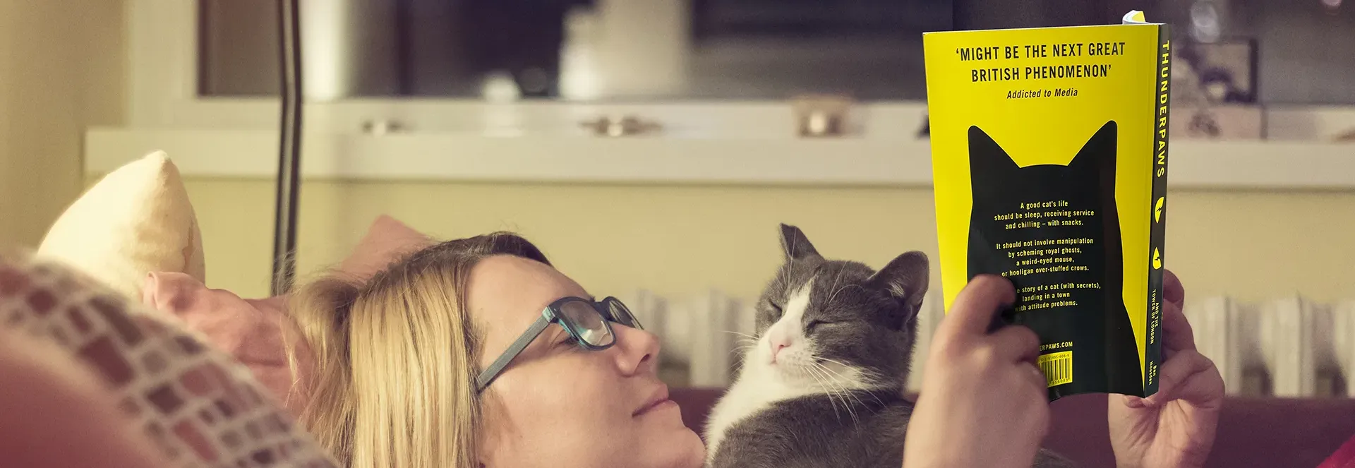 Person reading a book with a cat resting on their chest.