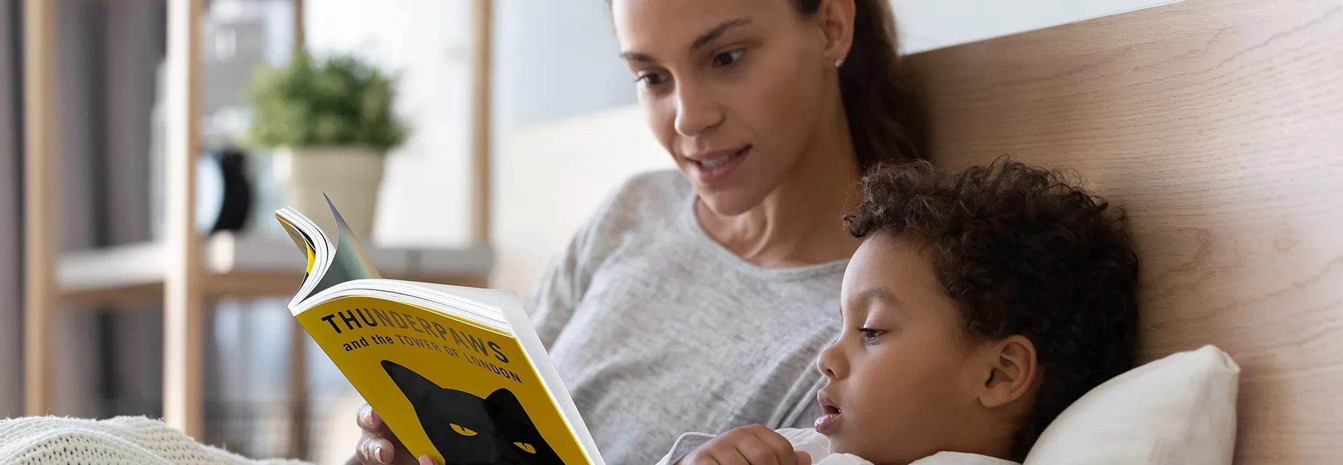 Woman and child reading a book together in bed.