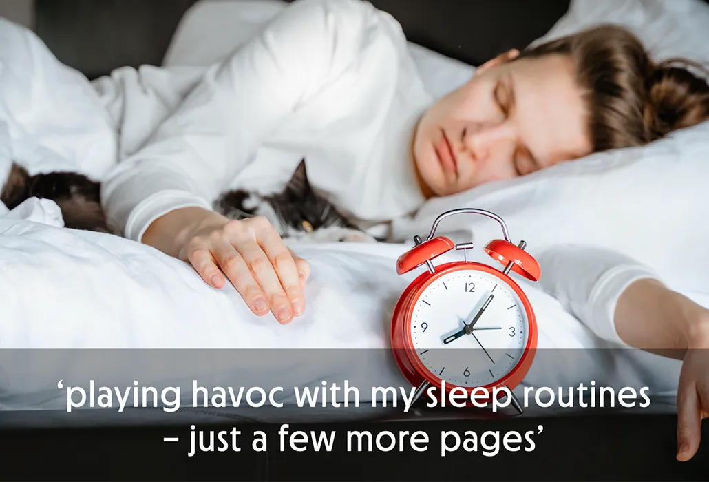 Woman sleeping in bed with a red alarm clock and a cat, with the quote “playing havoc with my sleep routines – just a few more pages.”