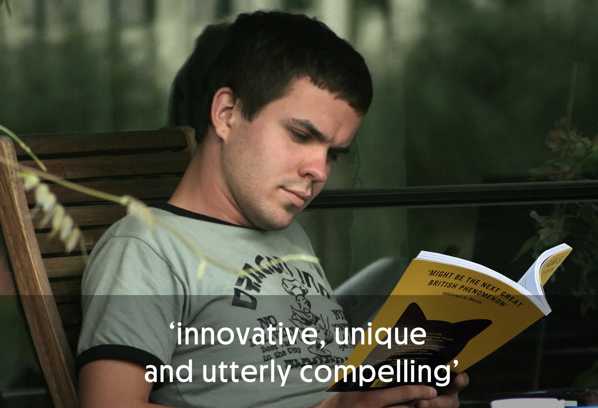 Man reading a book with a cat silhouette on the cover.