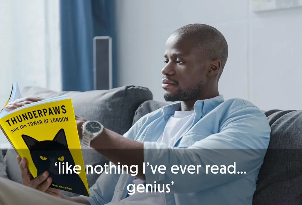 Man reading 'Thunderpaws and the Tower of London' on a couch, with the quote “like nothing I’ve ever read… genius”