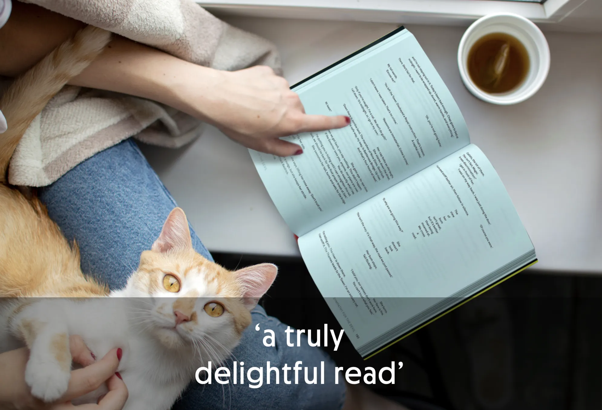 Person reading a book with a cat on their lap and a cup of tea nearby.
