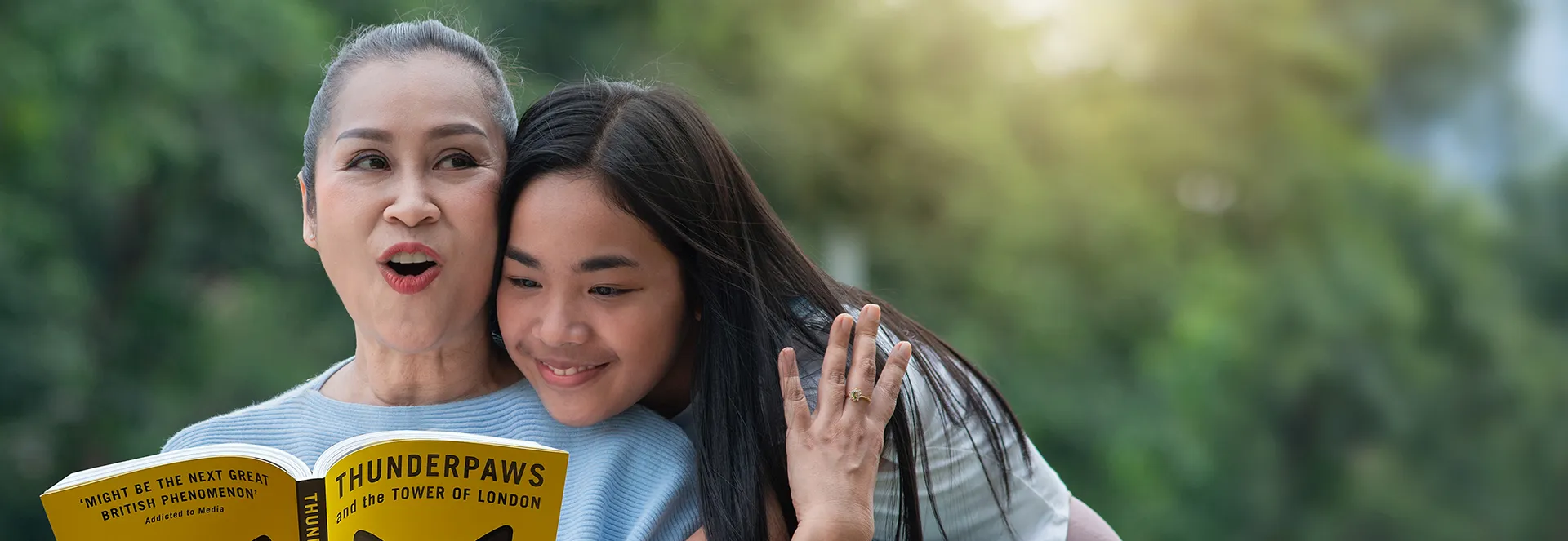 Two people reading a book titled 'Thunderpaws' outdoors, with greenery in the background.