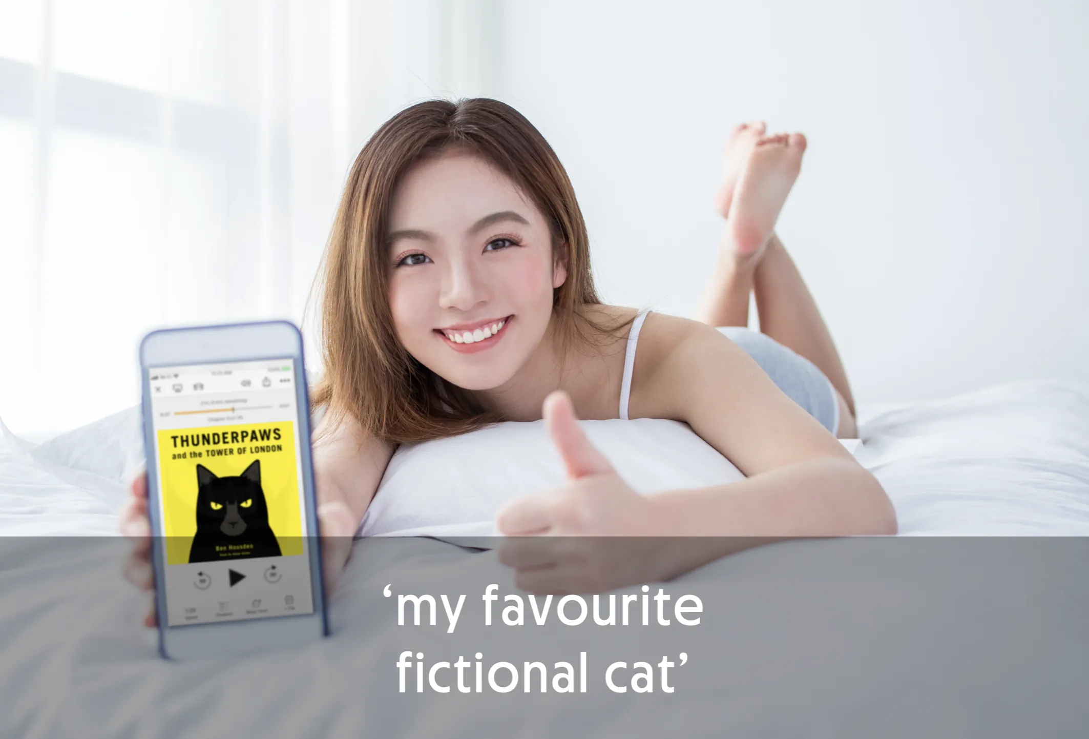 Smiling person holding a phone displaying a book cover, giving a thumbs up.