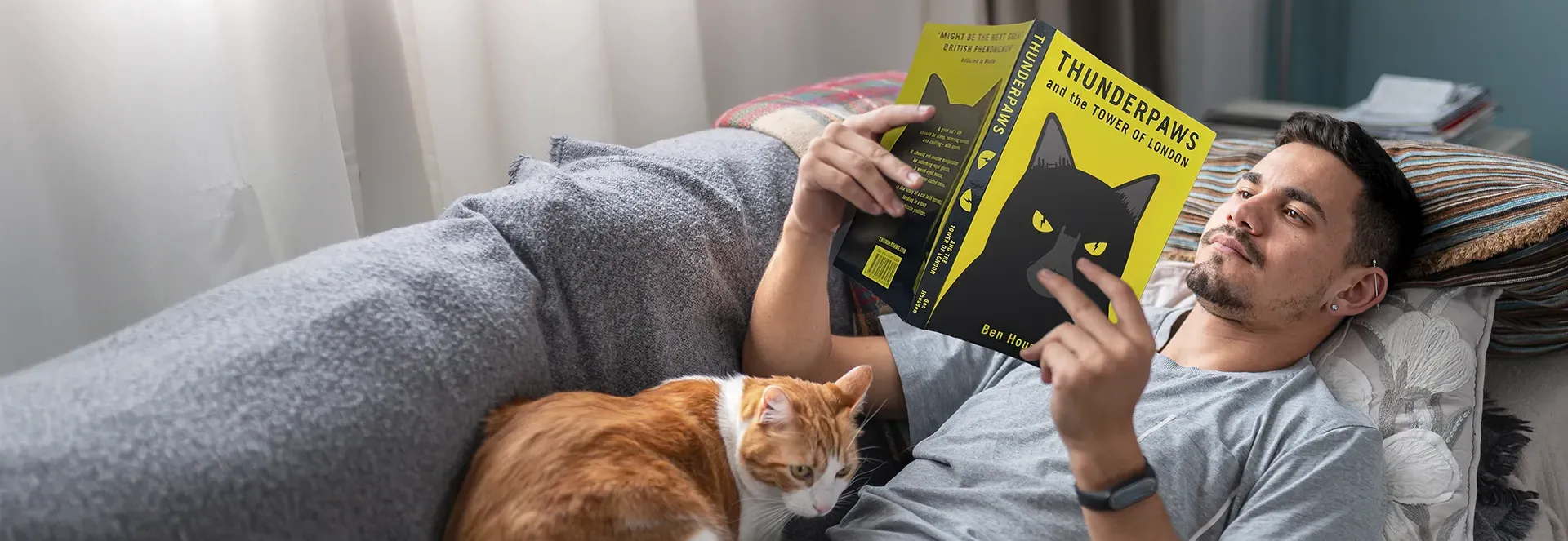 Man reading a book with a cat on his lap.