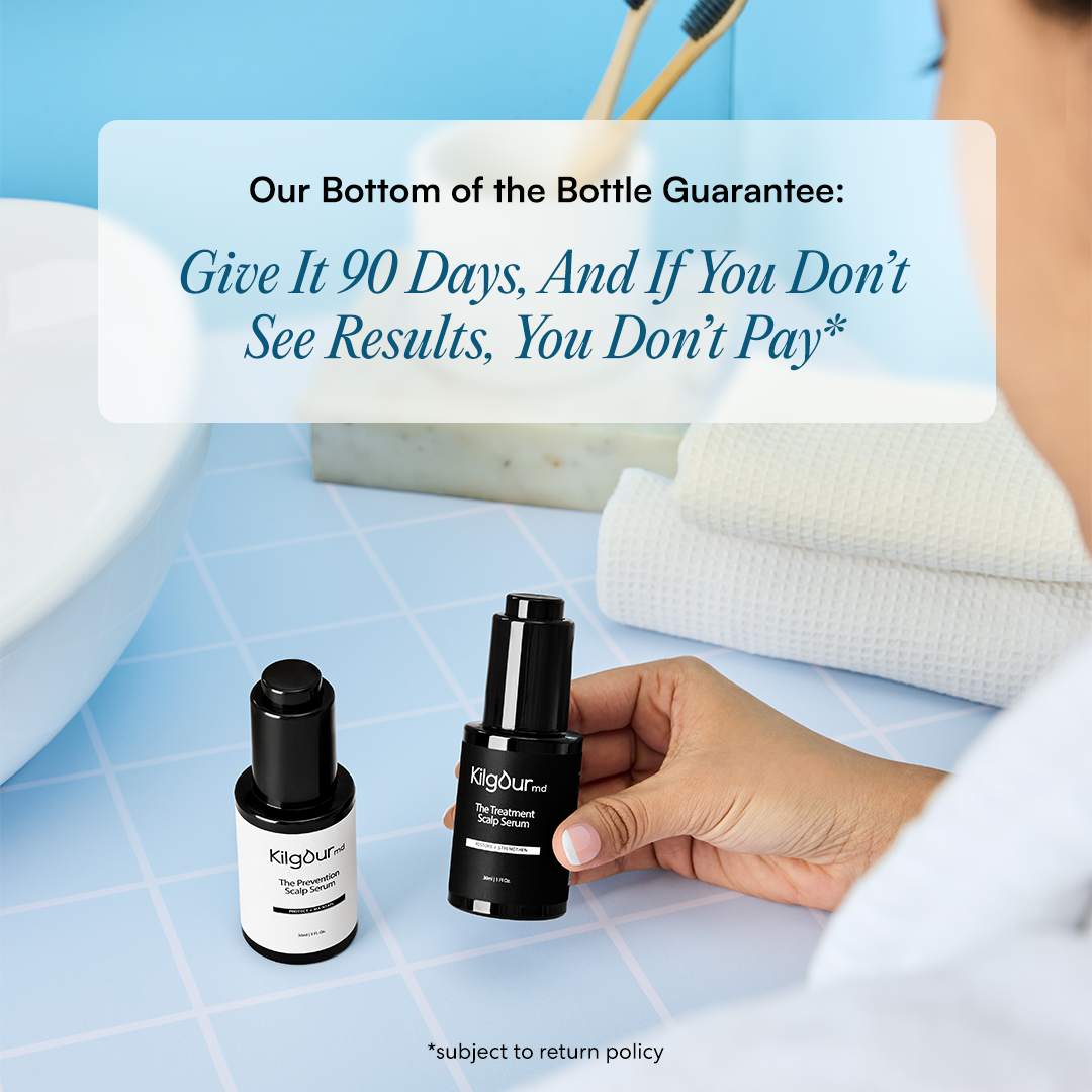 Two bottles of scalp serum held by a hand on a tiled surface.