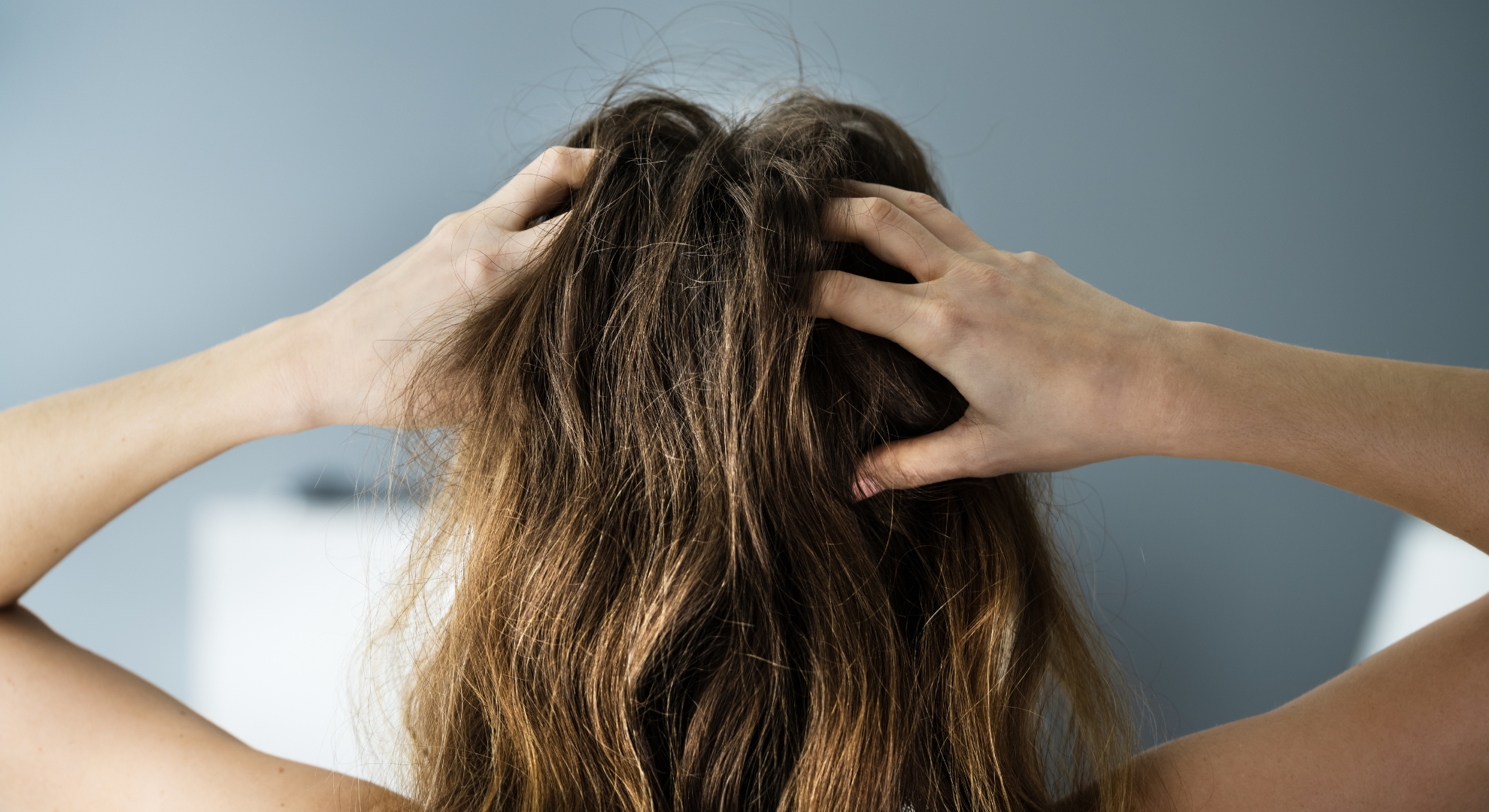 Person with long hair holding their head with both hands.