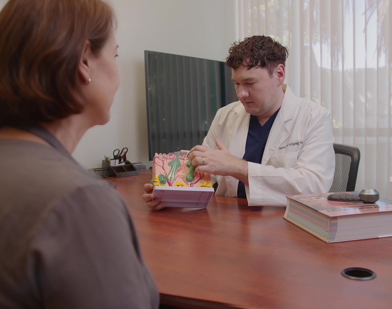 Doctor showing anatomical model to a patient in an office.