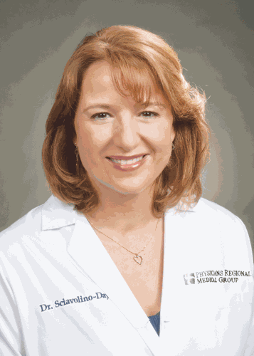 Headshot of a smiling woman with reddish-brown hair wearing a white lab coat.