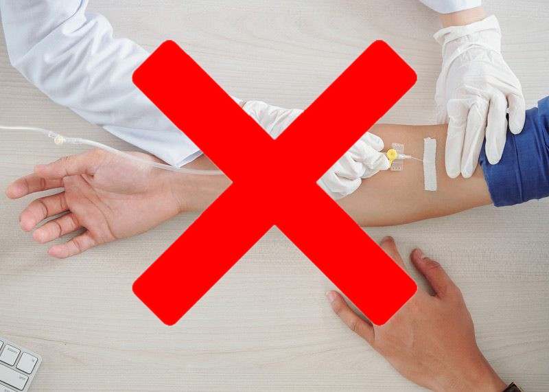Red cross over a medical procedure on an arm.
