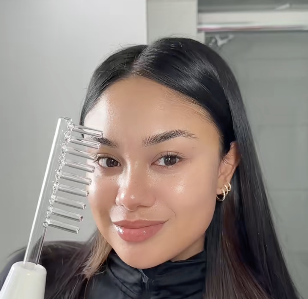 Person holding a clear comb, smiling in a bathroom setting.