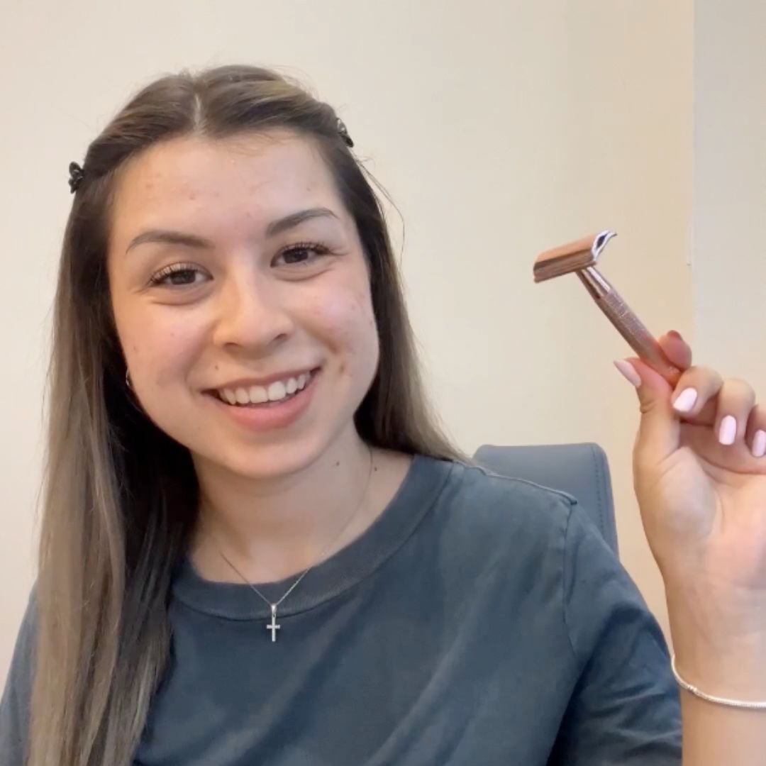 Smiling person holding a razor in hand.