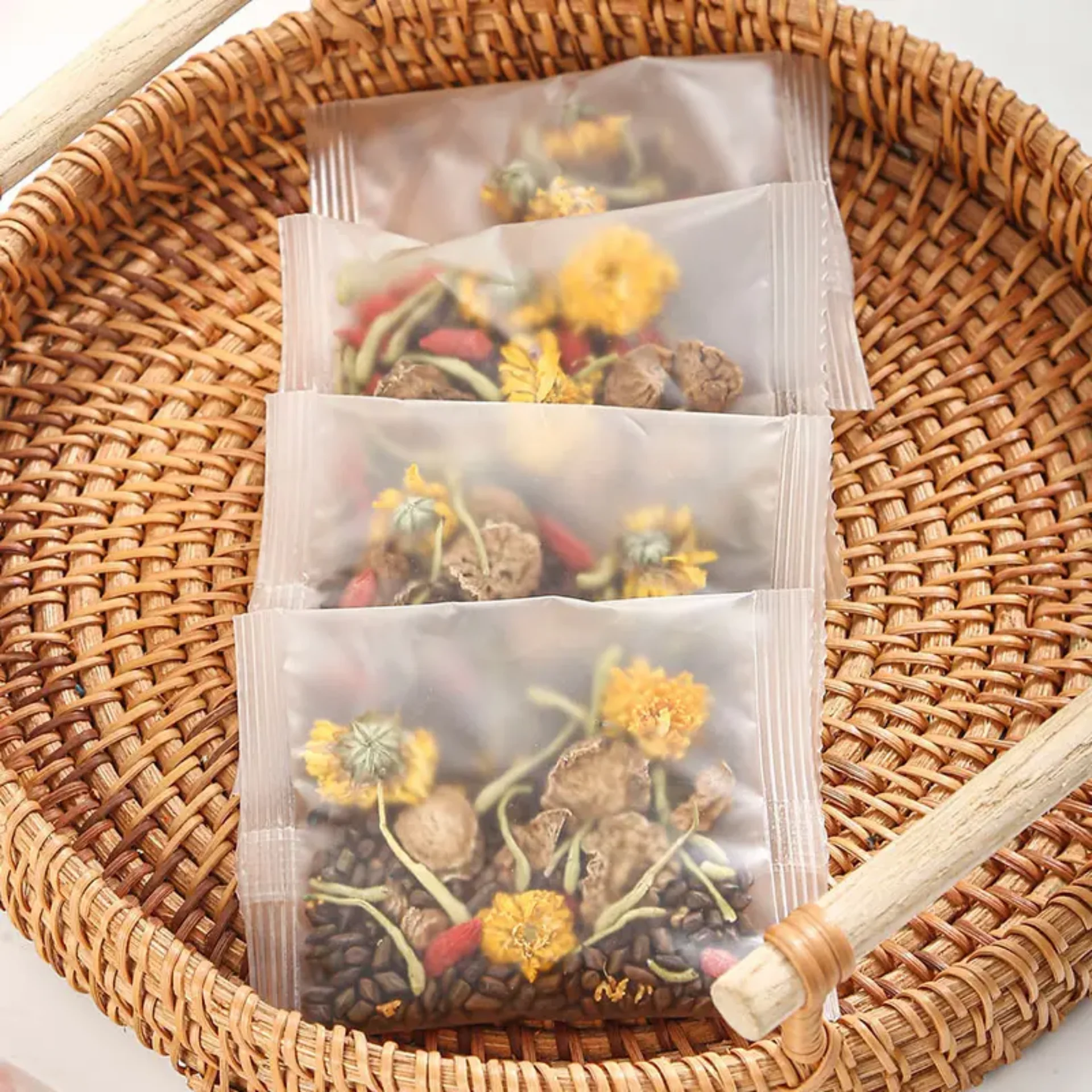 Four herbal sachets with dried flowers in a woven basket.