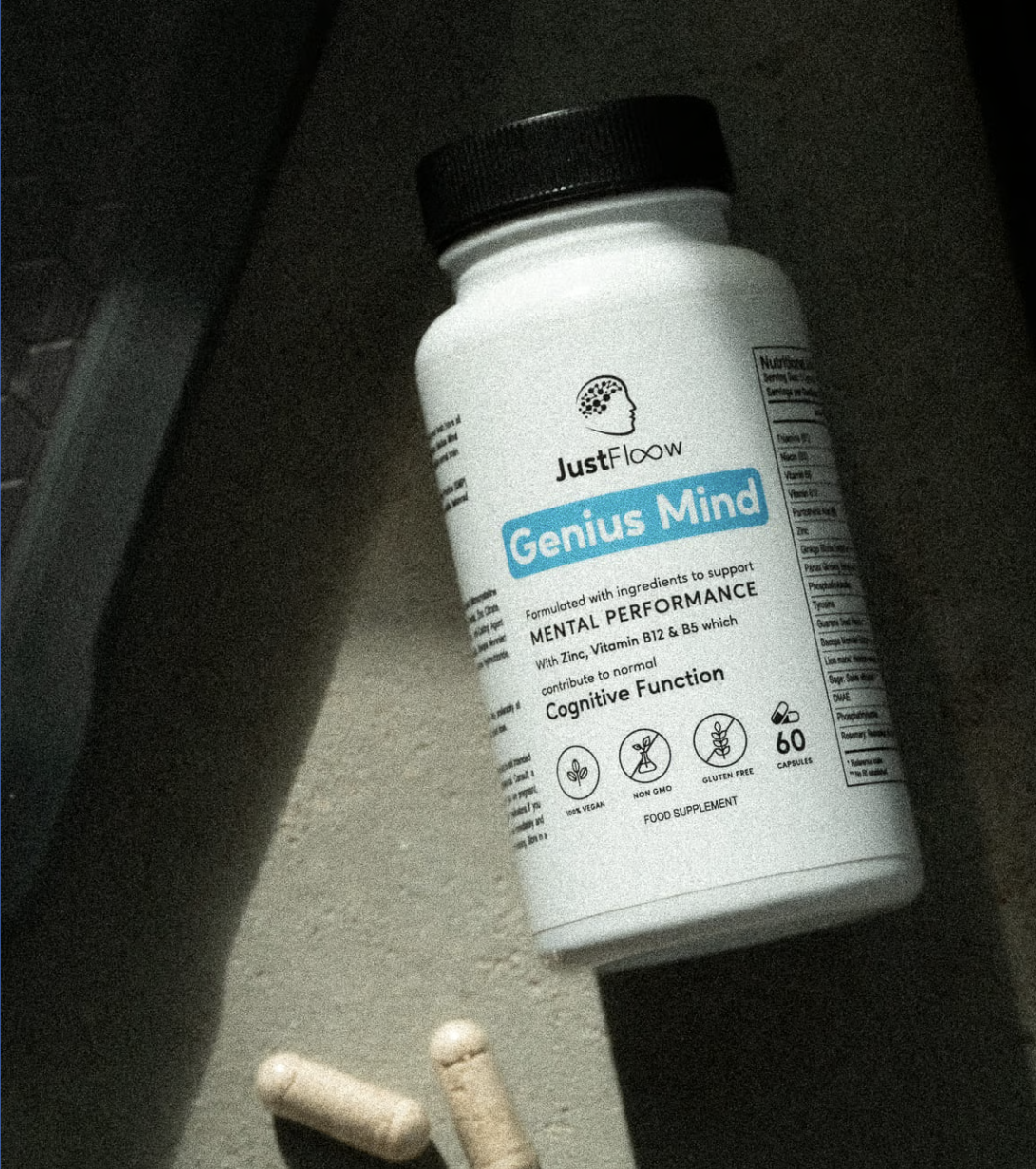 White bottle labeled 'Genius Mind' with capsules nearby on a surface.
