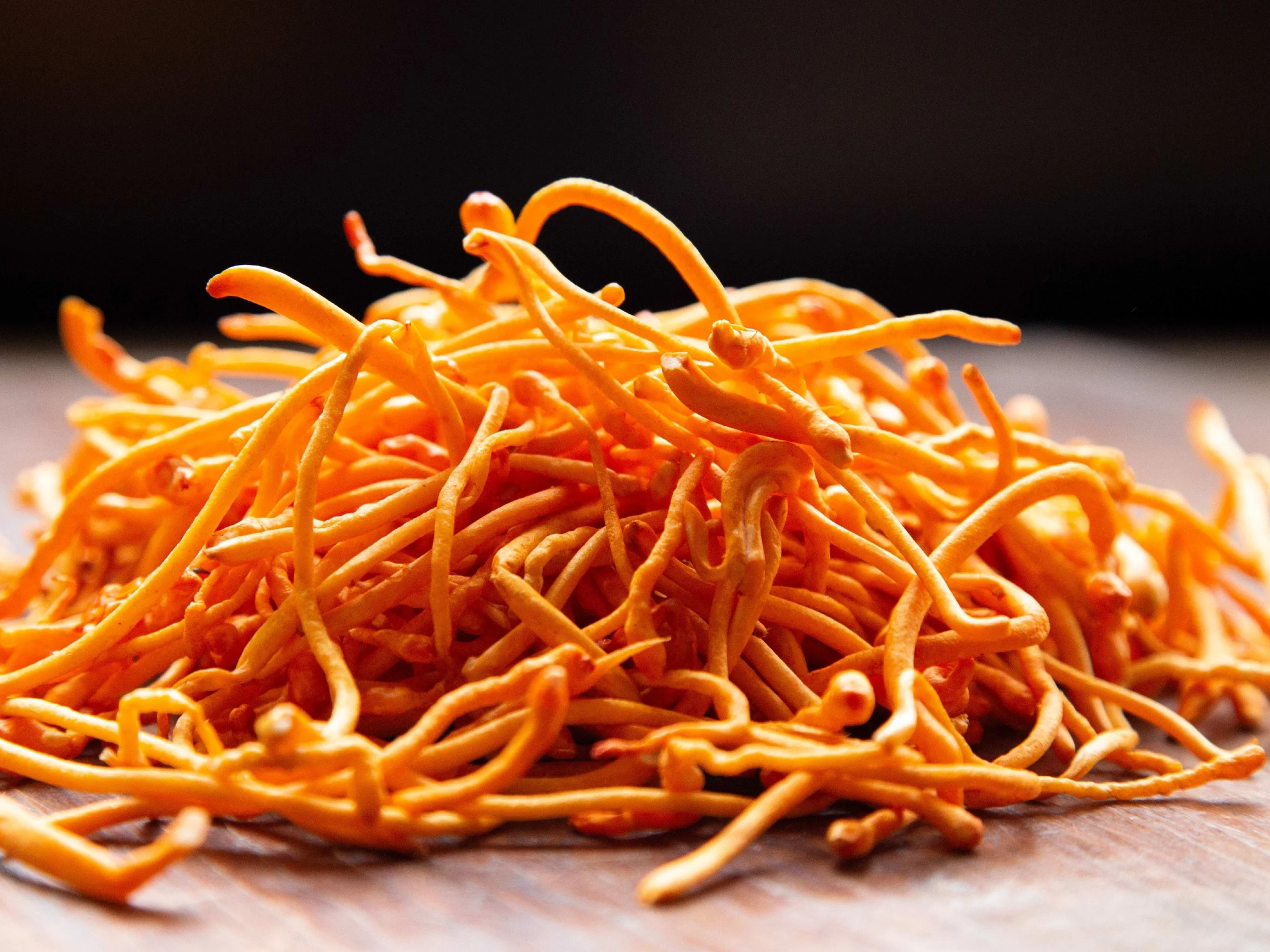 Pile of orange, noodle-like strands on a wooden surface.