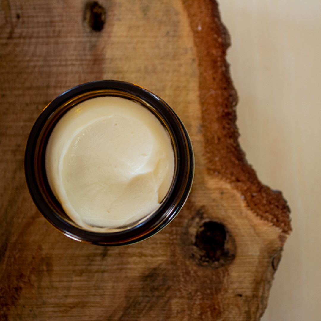 A jar of cream on a wooden surface.